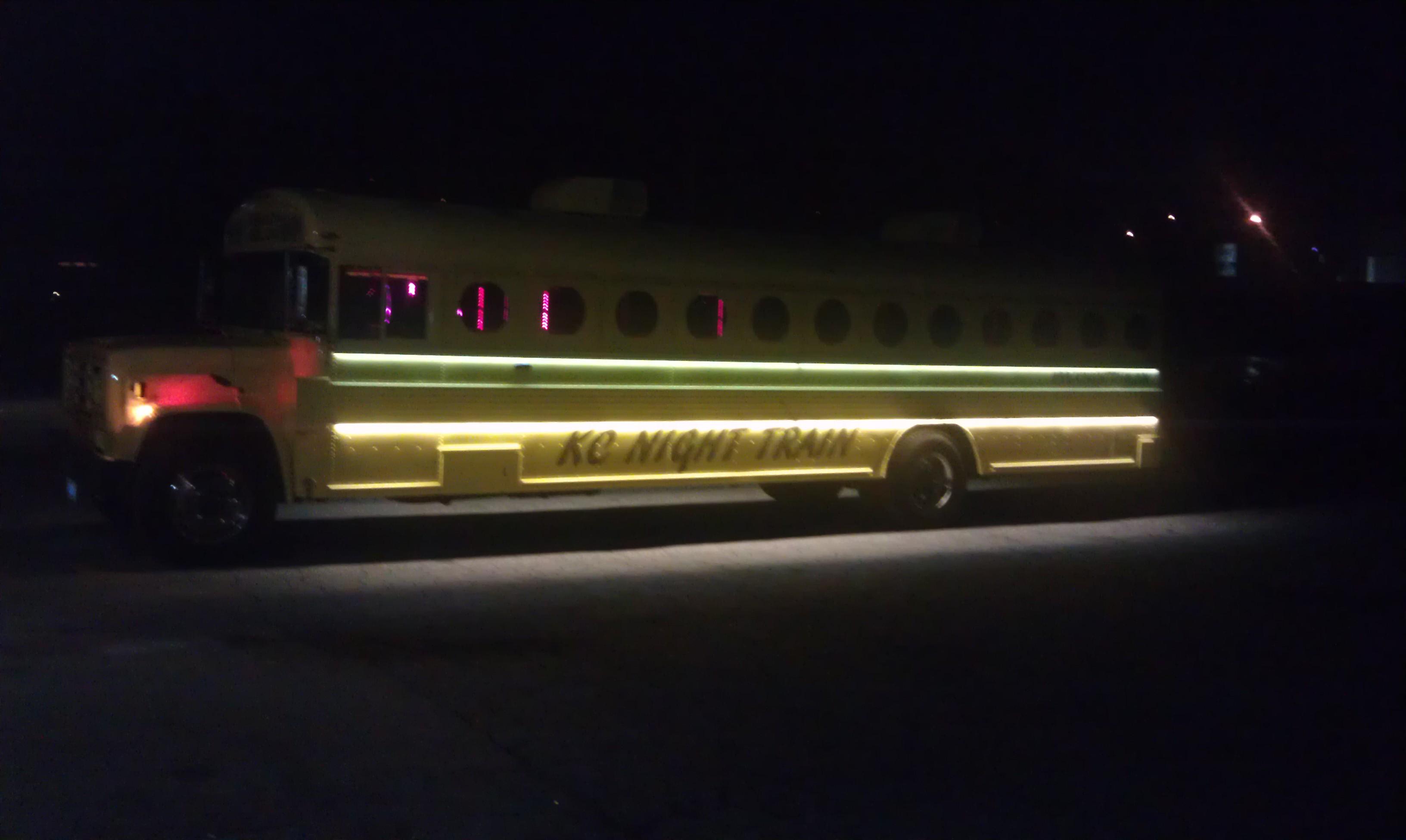 Night view of the Mellow Yellow Party Bus on the driver's side